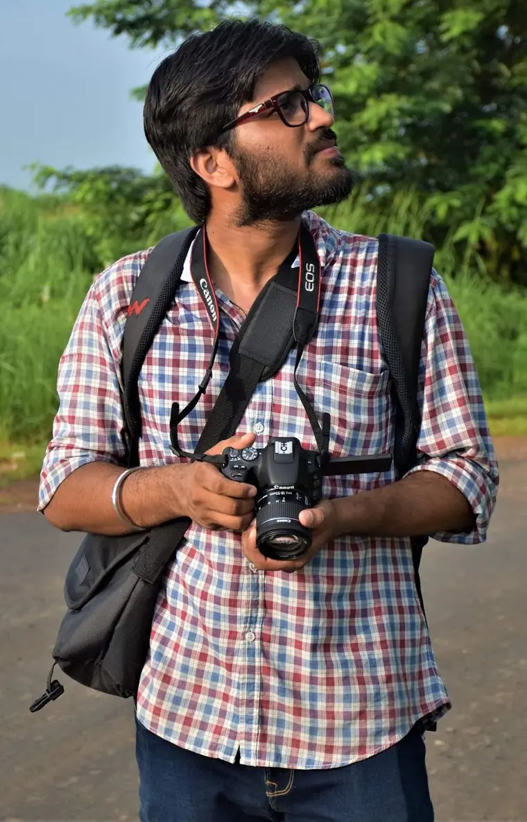 Kishan Tiwari holding a camera in the field.
